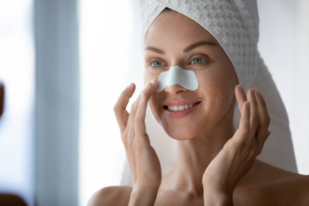 Close up 30s woman after shower with towel on head using ayurvedic remedies for nose strips deep purifying treatment to unclog pores prevent remove blackheads, leaving skin clear and smooth, skincare concept